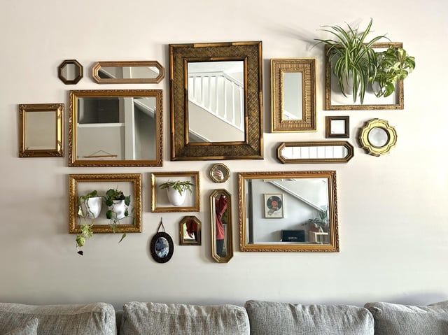 a living room wall filled with lots of framed pictures and mirrors on it's side