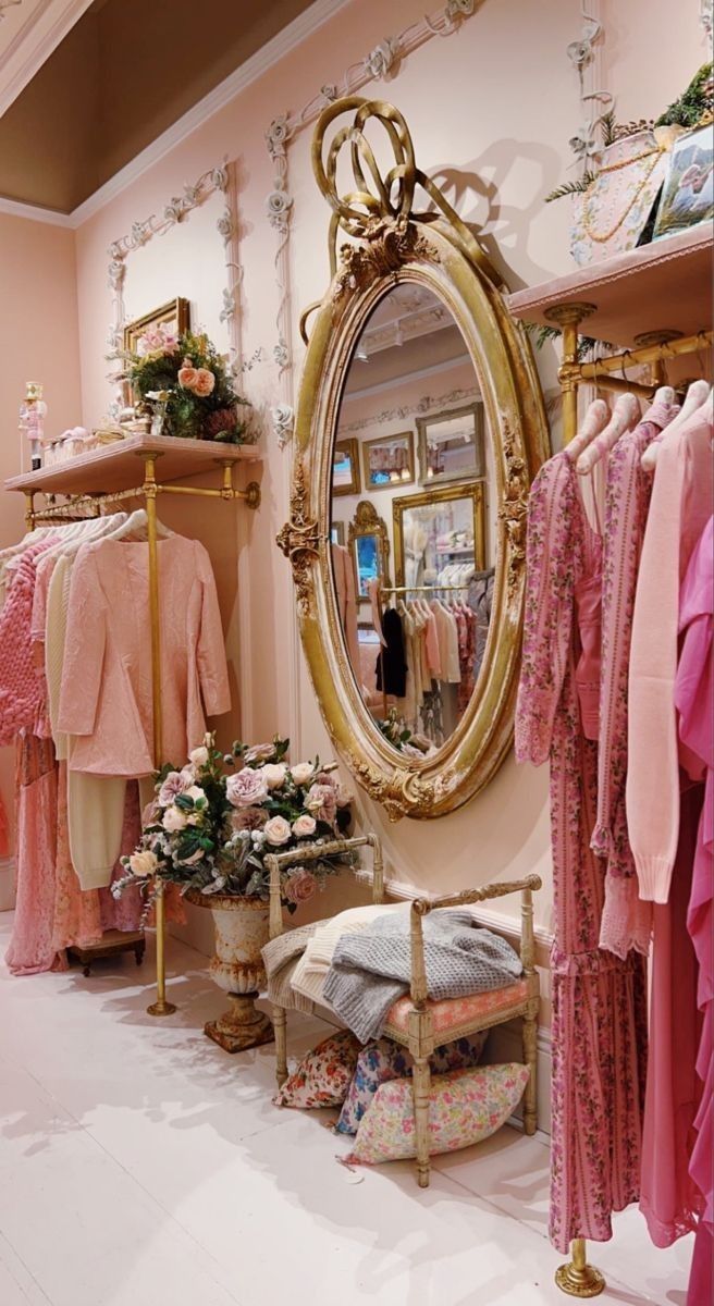 there is a clothing store with pink and gold clothes on racks in front of the mirror