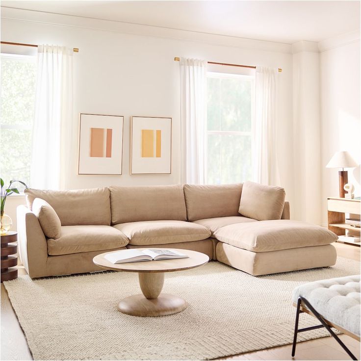 a living room with a large sectional couch and coffee table in front of two windows