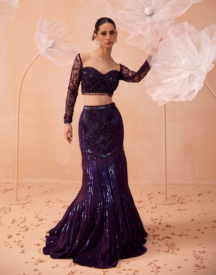 A striking purple mermaid-style lehenga is highlighted with sequins and intricate geometric patterns. Paired with a matching blouse and dupatta, this ensemble blends modern elegance with detailed craftsmanship, making it a perfect choice for any special event. Wedding Lehanga For Bridesmaid, Indian Mermaid Gown, Outfits For Cocktails Night, Fishcut Lehenga Bridal, Cocktail Lehenga Outfit, Thai Wedding Dress Purple, Bridesmaid Sangeet Outfit, Lehenga For Sangeet Night, Fishcut Lehenga Pattern