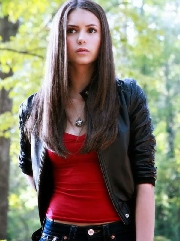 a woman standing in the woods with her hand on her hip and looking at the camera