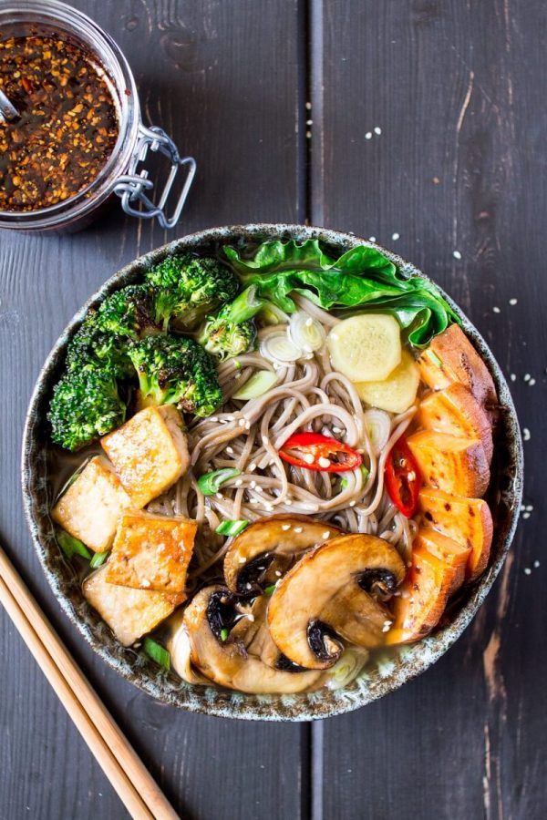 a bowl filled with noodles, broccoli and mushrooms next to chopsticks