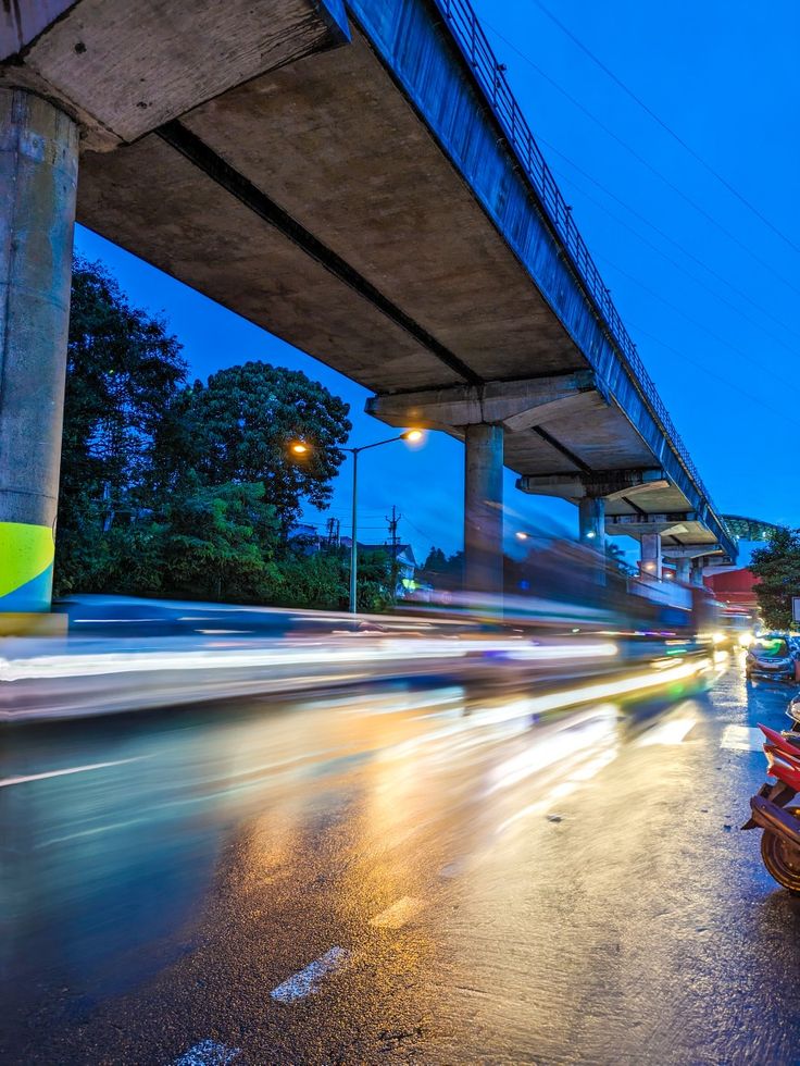 the cars are driving under an overpass at night