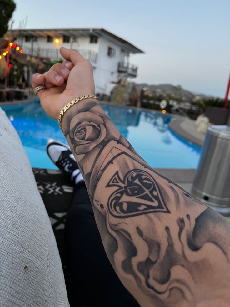 a man with a tattoo on his arm next to a swimming pool