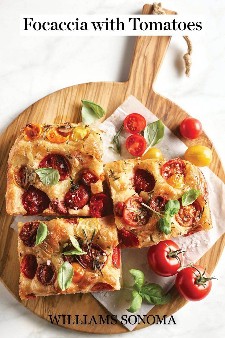 food on a wooden plate with tomatoes and basil in the middle, along with text that reads focaccia with tomatoes