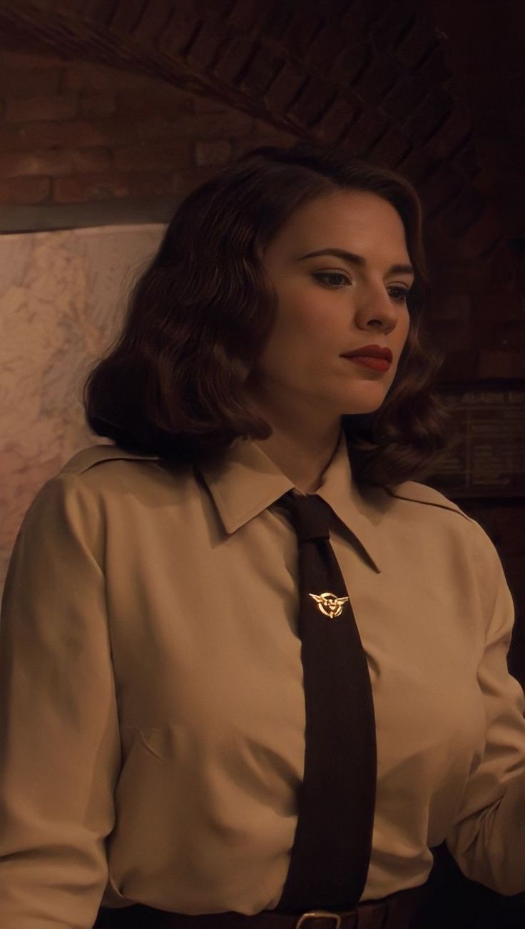 a woman in a dress shirt and tie standing next to a wall with a clock on it