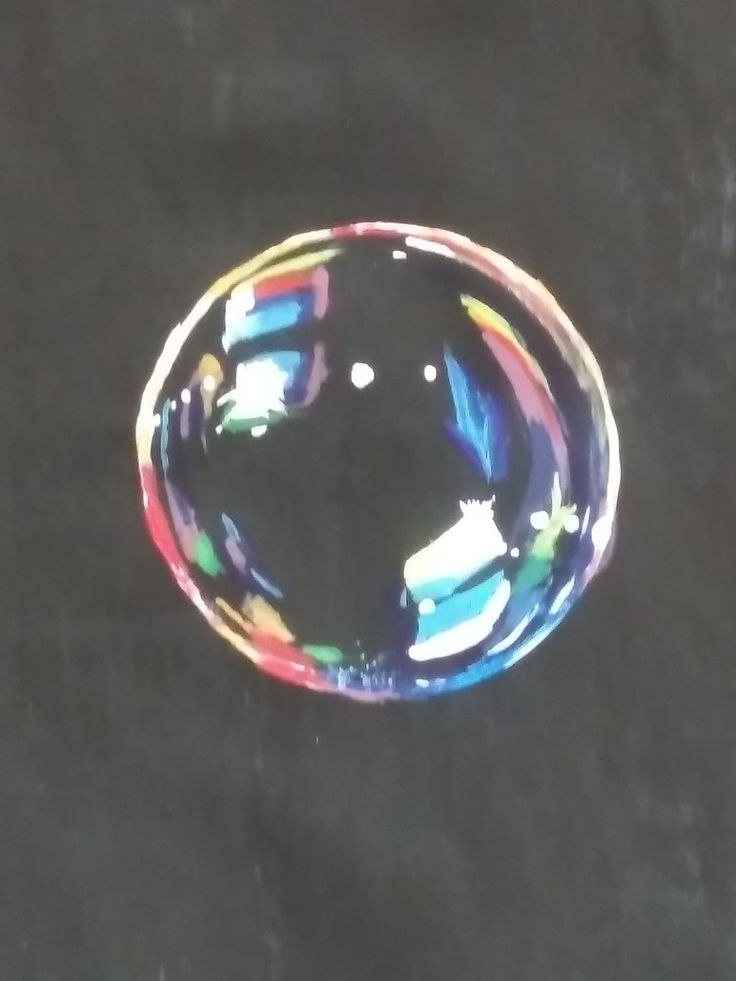 a soap bubble floating on top of a black surface