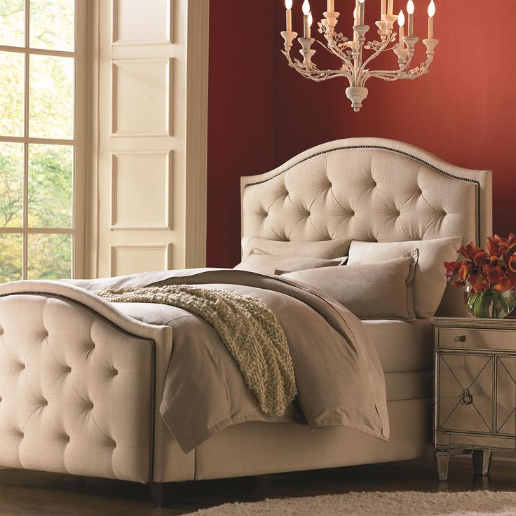 a white bed sitting next to a window in a room with red walls and furniture