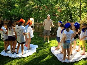 a group of people standing around each other on towels in the grass with trees in the background