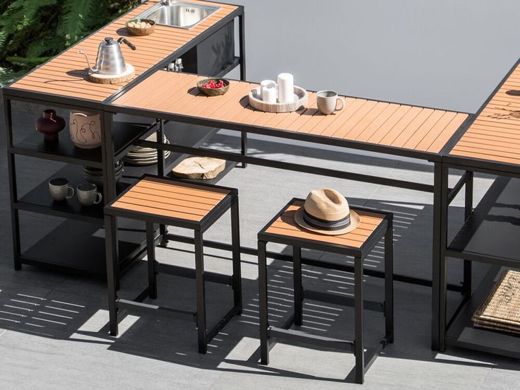 an outdoor table with three stools and plates on it