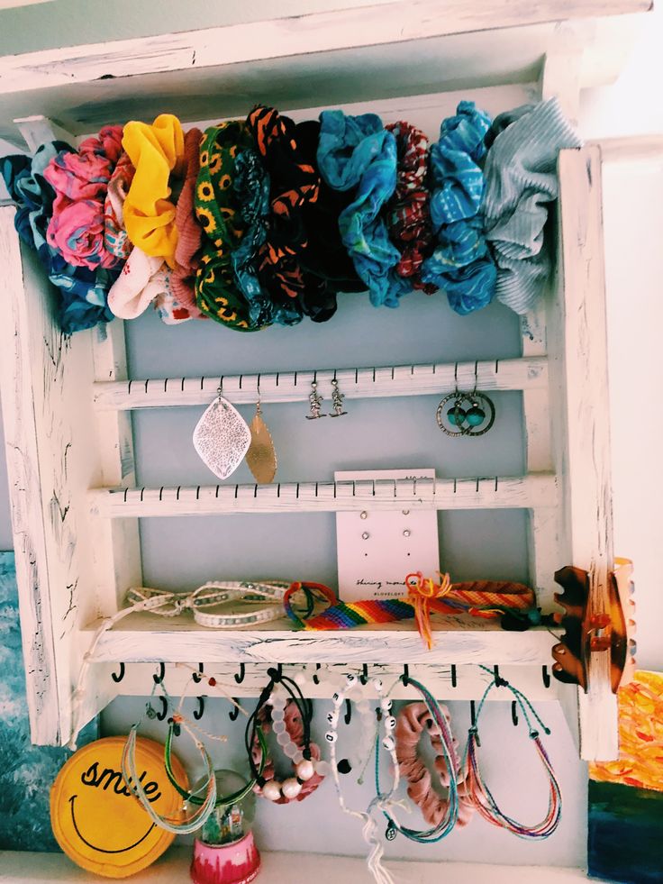 a white shelf filled with lots of bracelets and other items on top of it