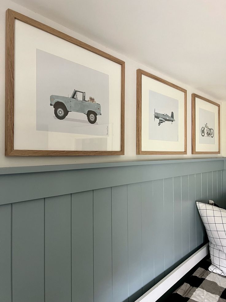 three framed pictures hang on the wall next to a bench with a checkered cushion