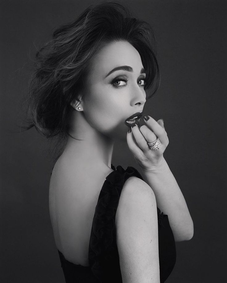 a black and white photo of a woman in a dress holding a pastry up to her mouth