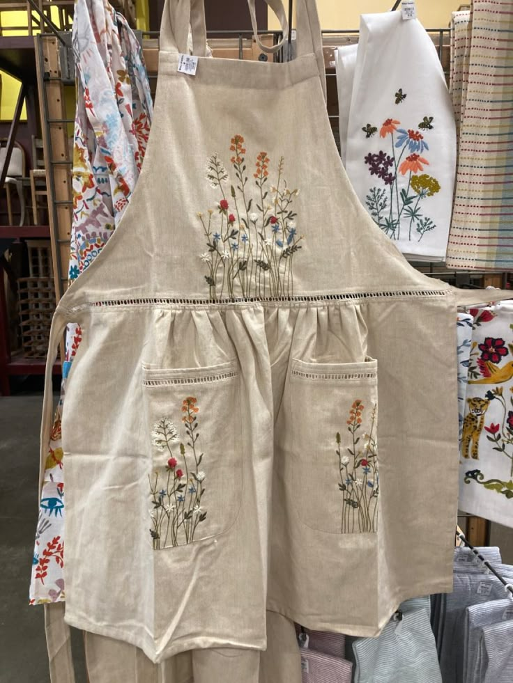 aprons with embroidered flowers are on display in a store