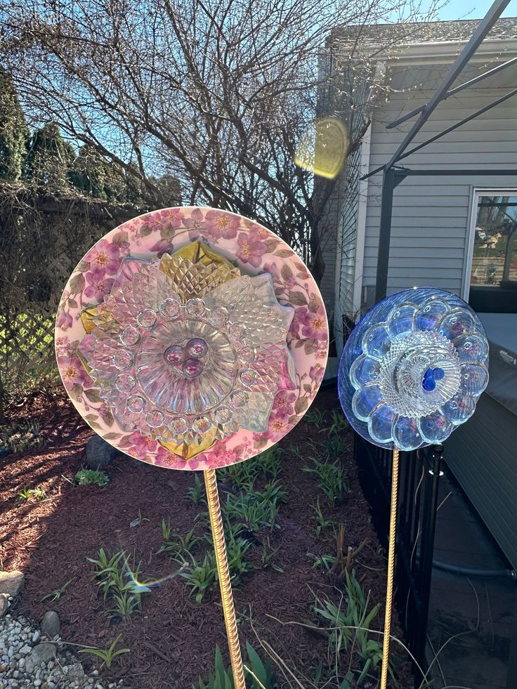 two colorful glass plates sitting on top of a metal pole in front of a house