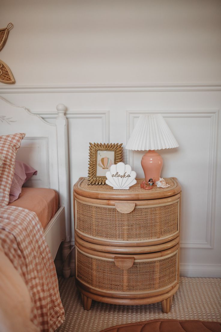 a bed room with a neatly made bed and a wicker dresser next to it