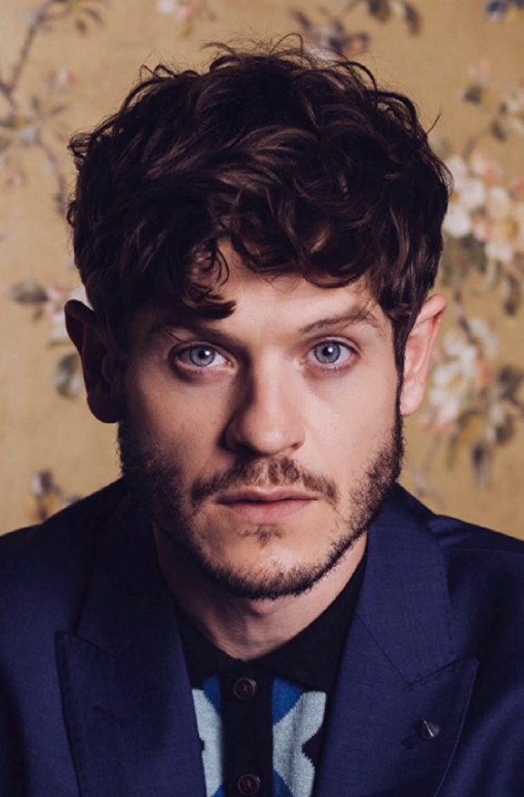 a man in a blue suit and tie looking at the camera with an intense look on his face