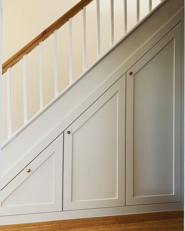 an empty room with white cabinets under the stairs