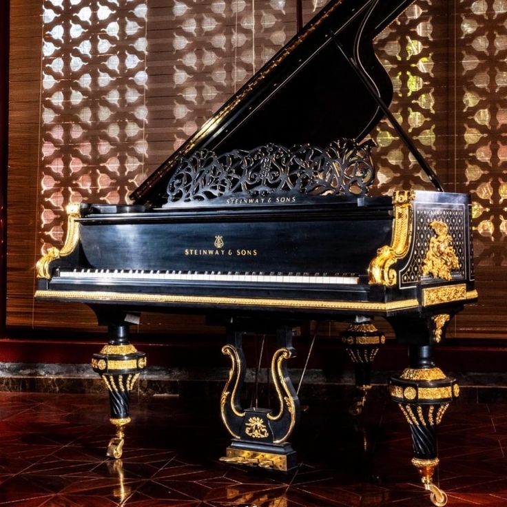 a grand piano sitting on top of a marble floor in front of a decorative wall