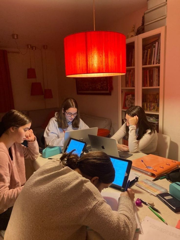 three women sitting at a table with laptops