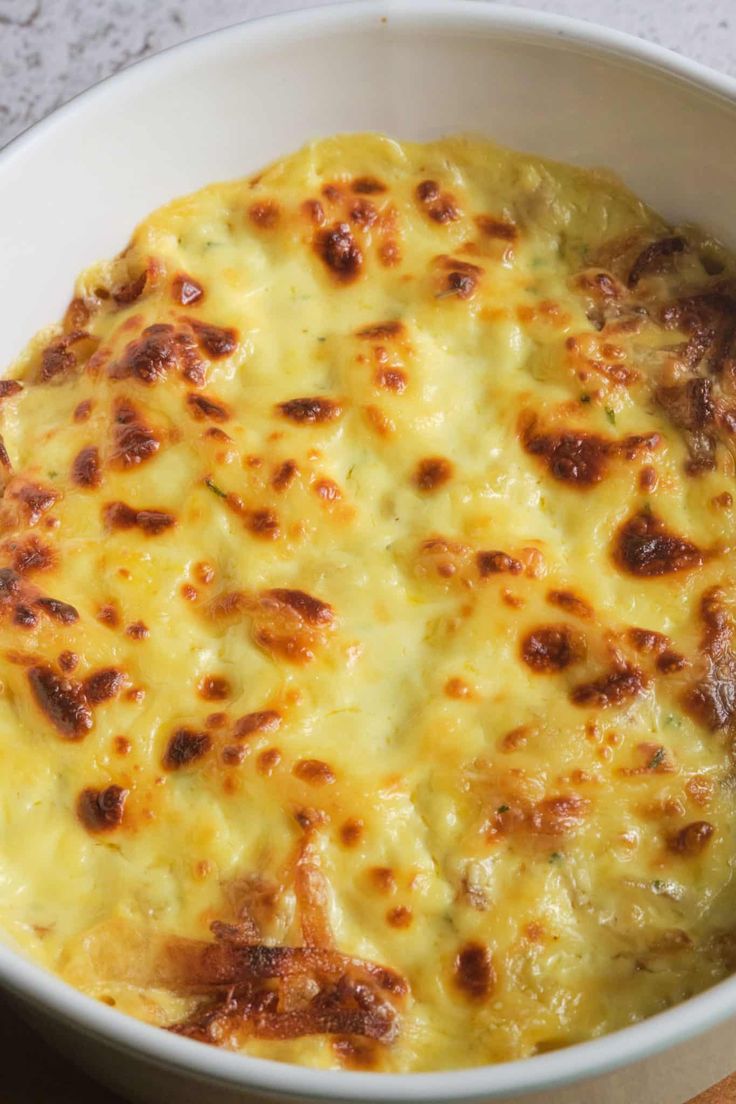 a white bowl filled with cheese on top of a wooden table