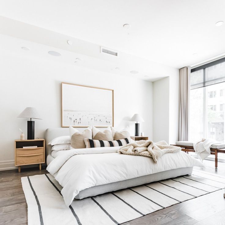 a large white bed sitting in a bedroom next to a window