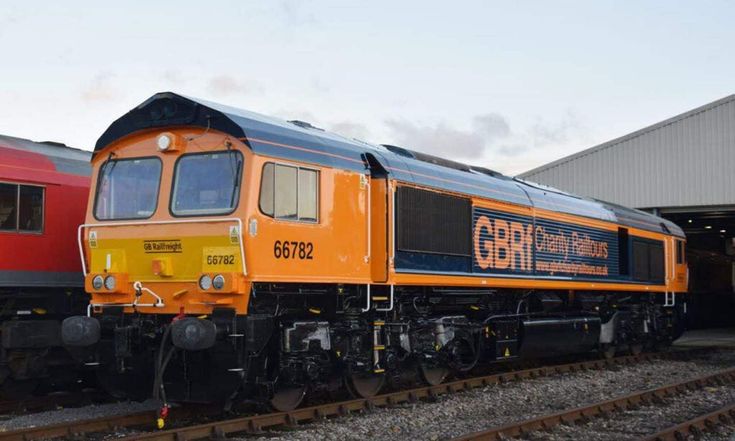 two trains are parked next to each other on the tracks in front of a building