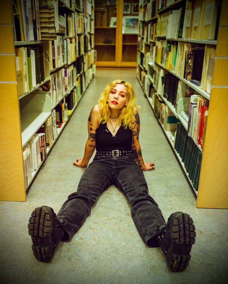 a woman is sitting on the floor in a library with her legs crossed and feet spread out