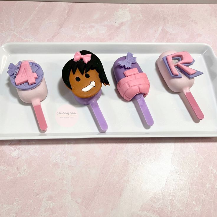 three decorated cupcakes sitting on top of a white tray with pink and purple icing