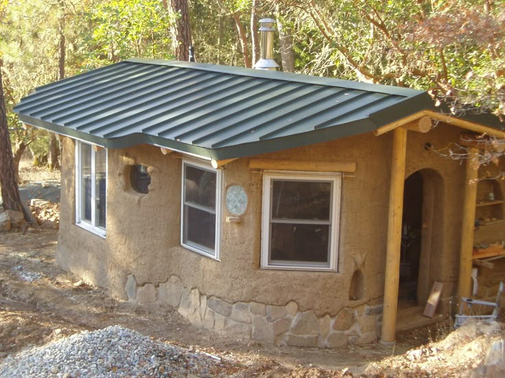 a small building with a metal roof in the woods