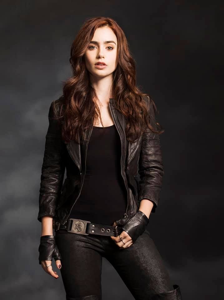 a woman in black jacket and leather pants standing with her hands on her hipss