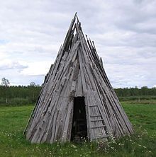 an old wooden structure sitting in the middle of a field