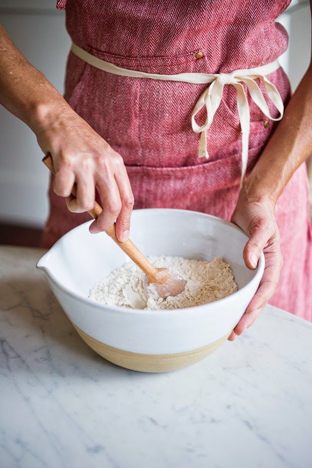 a woman in an apron is mixing ingredients into a bowl