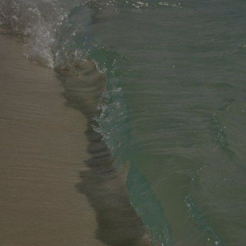 a person riding a surfboard on top of a wave in the ocean next to shore