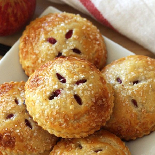 mini cranberry apple pies on a plate with an apple in the background