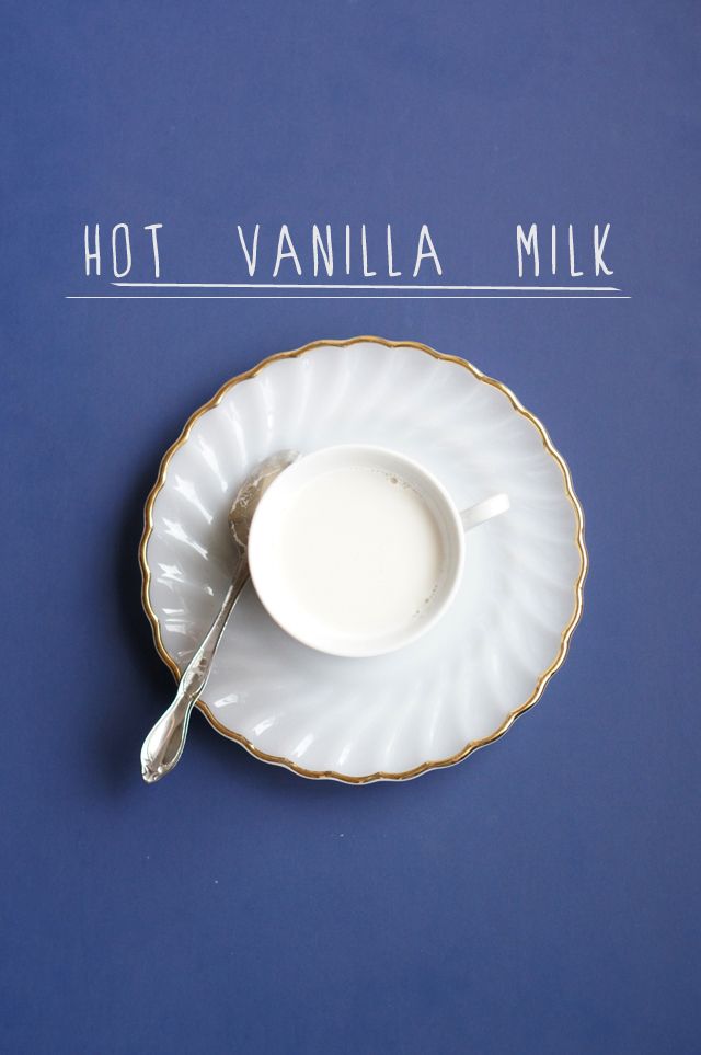 a white cup and saucer on a blue surface with the words hot vanilla milk