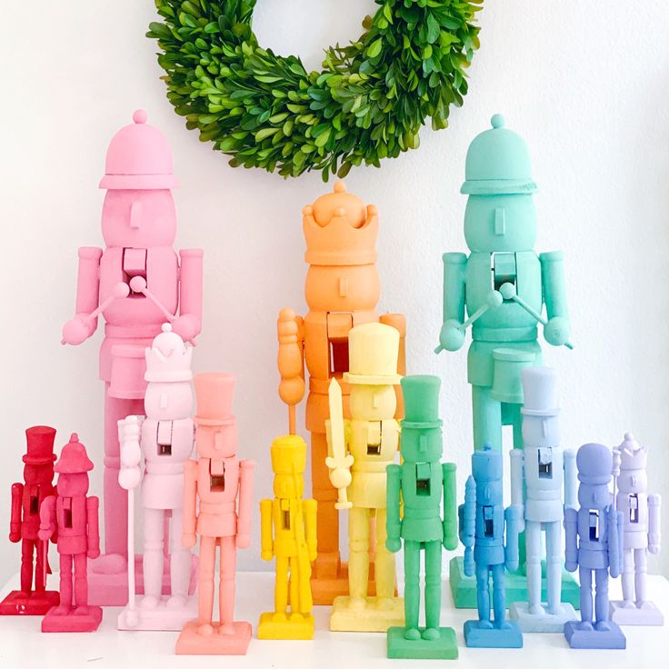 a group of small toy figures next to a wreath on a white wall with a green wreath behind them