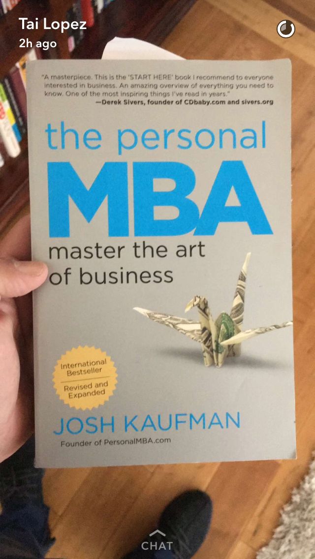 a person holding up a book in front of a bookshelf with the title'the personal mba master the art of business '