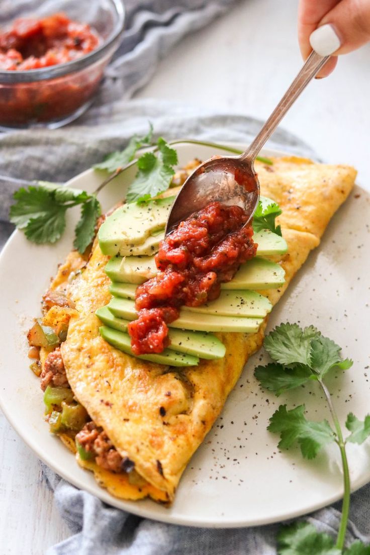 an omelet with salsa and avocado is being served on a plate