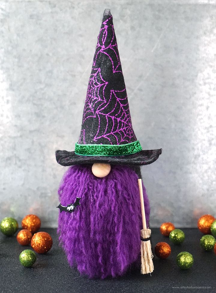 a purple and black witches hat on top of a purple bag with green decorations around it