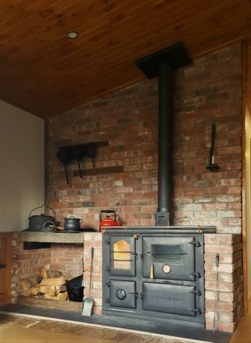 an old fashioned wood stove in a room with brick walls and wooden flooring on the ceiling