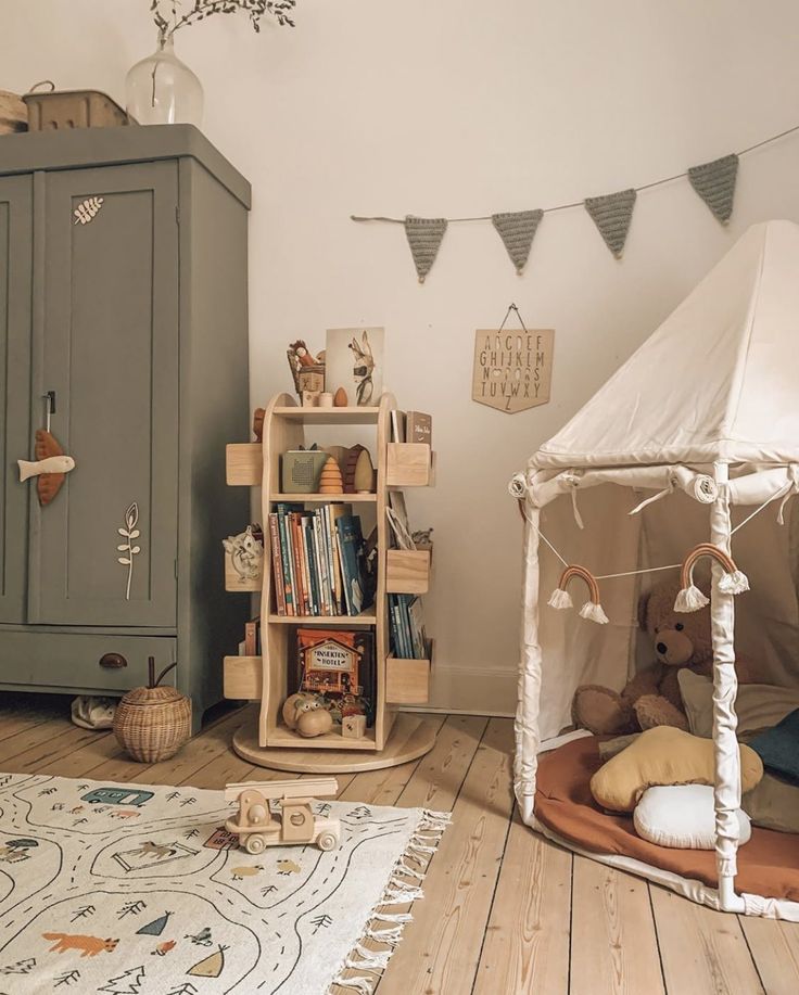 a child's room with a teepee tent, bookshelf and stuffed animals