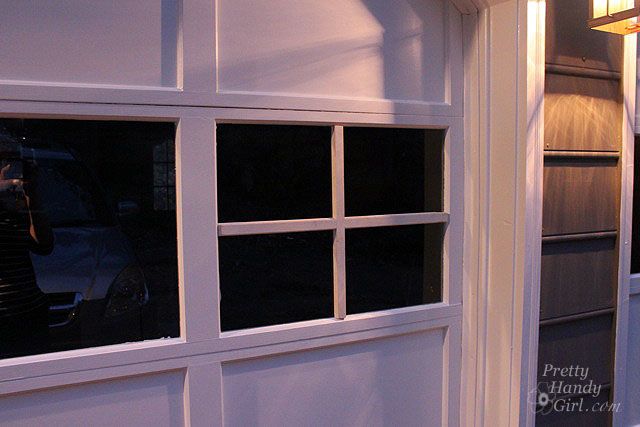 a white garage door with windows on both sides and a light hanging from the ceiling