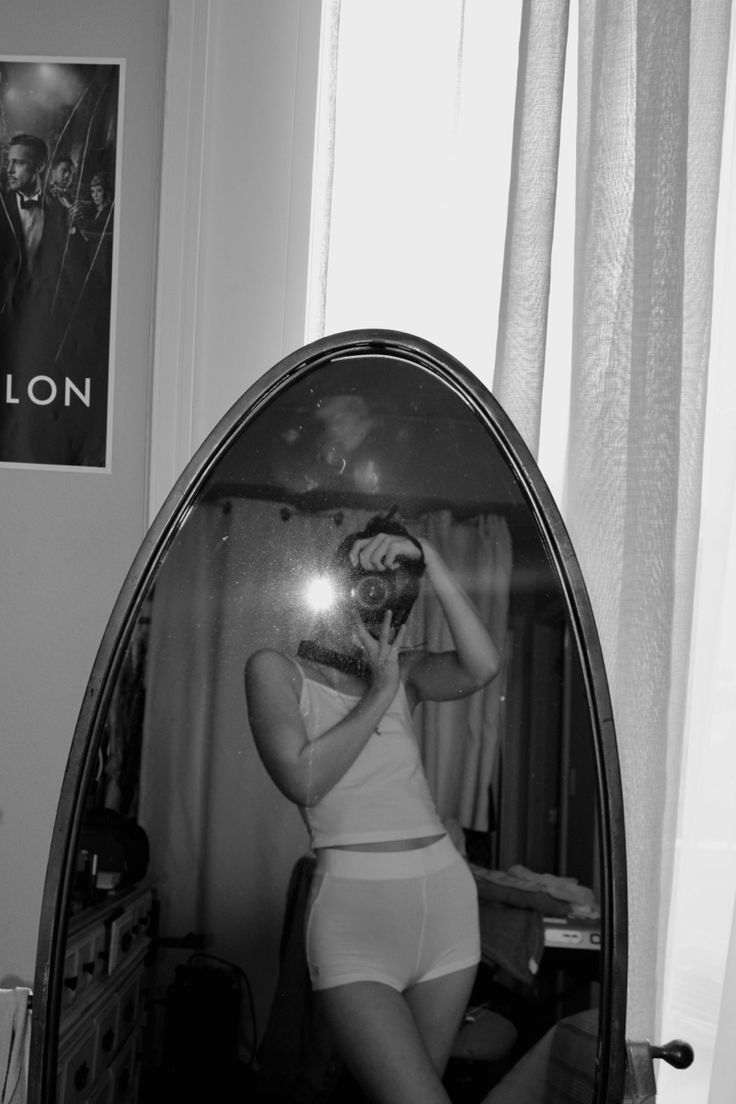 a woman taking a selfie in front of a mirror with the reflection of herself