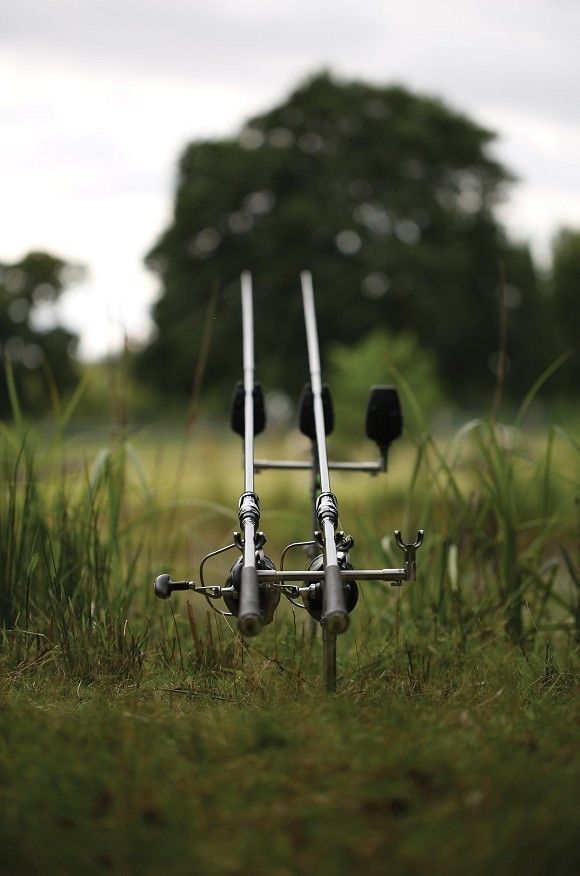 two fishing rods sitting in the grass next to each other with trees in the background