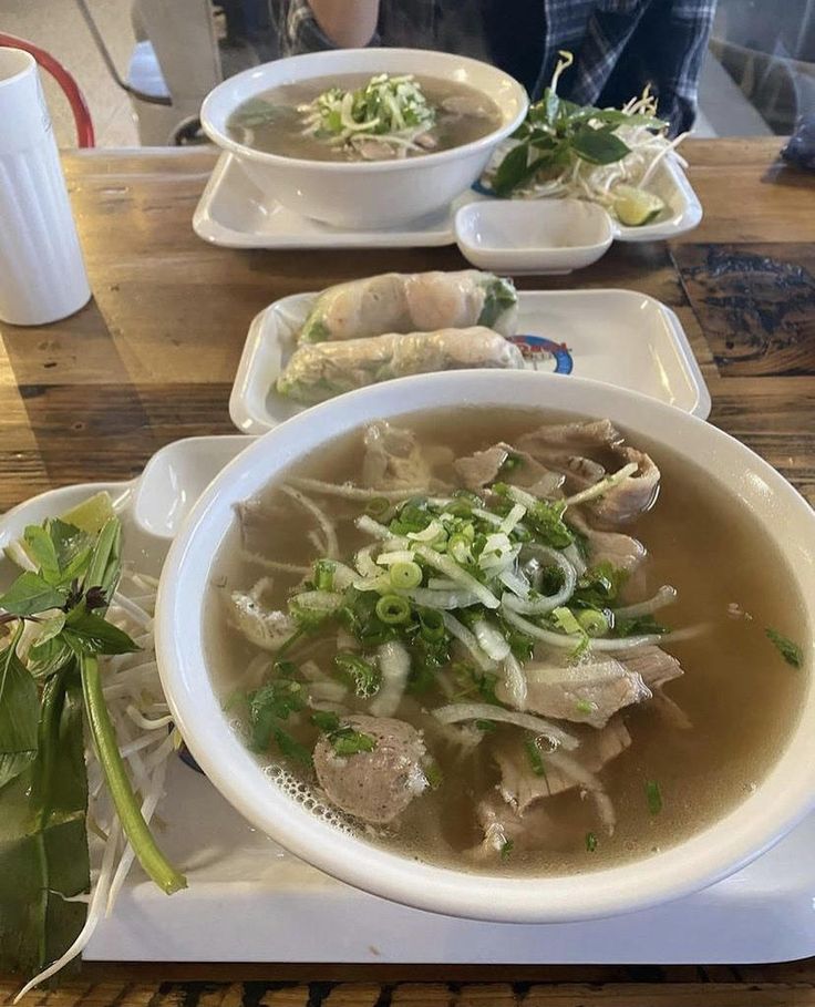 a bowl of soup with meat and vegetables on a plate next to another bowl of soup