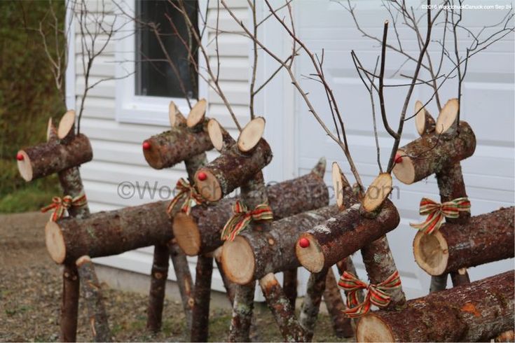 several wooden logs with bows tied to them in front of a white building and some trees