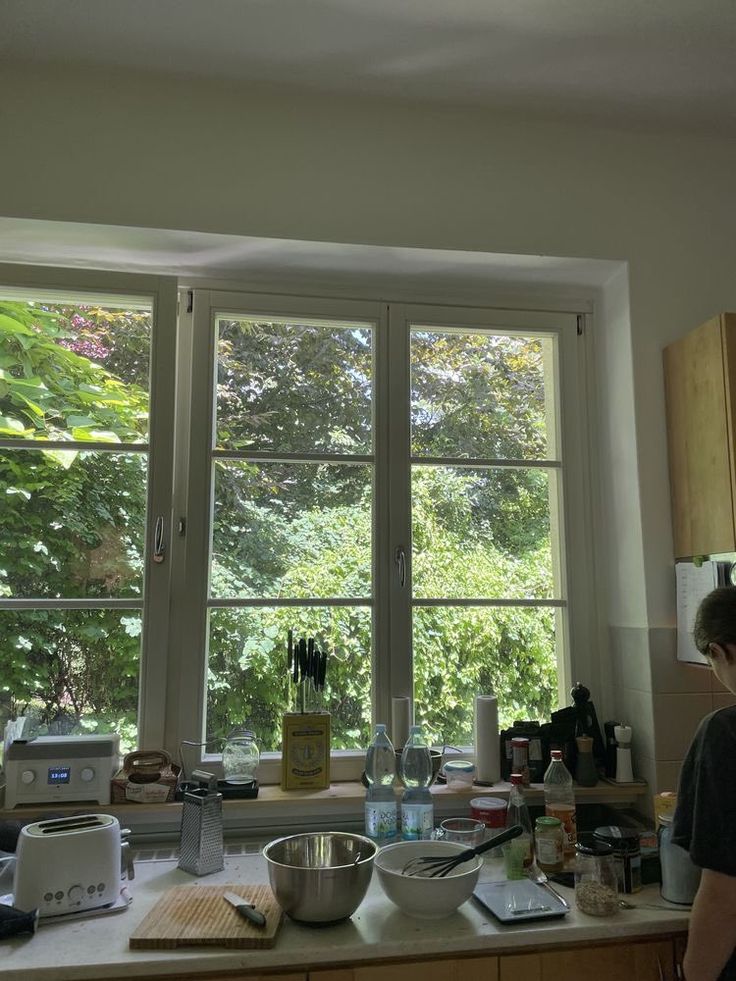 a man standing in front of a kitchen window next to a bowl on the counter