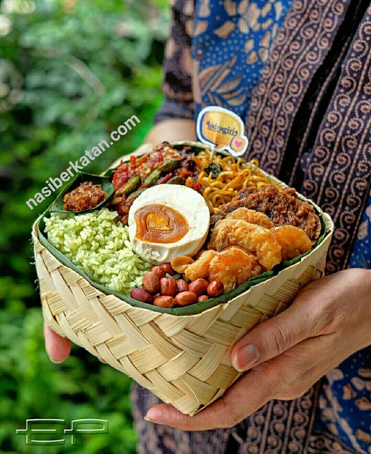 a person holding a basket filled with different types of food and dipping sauce on top of it