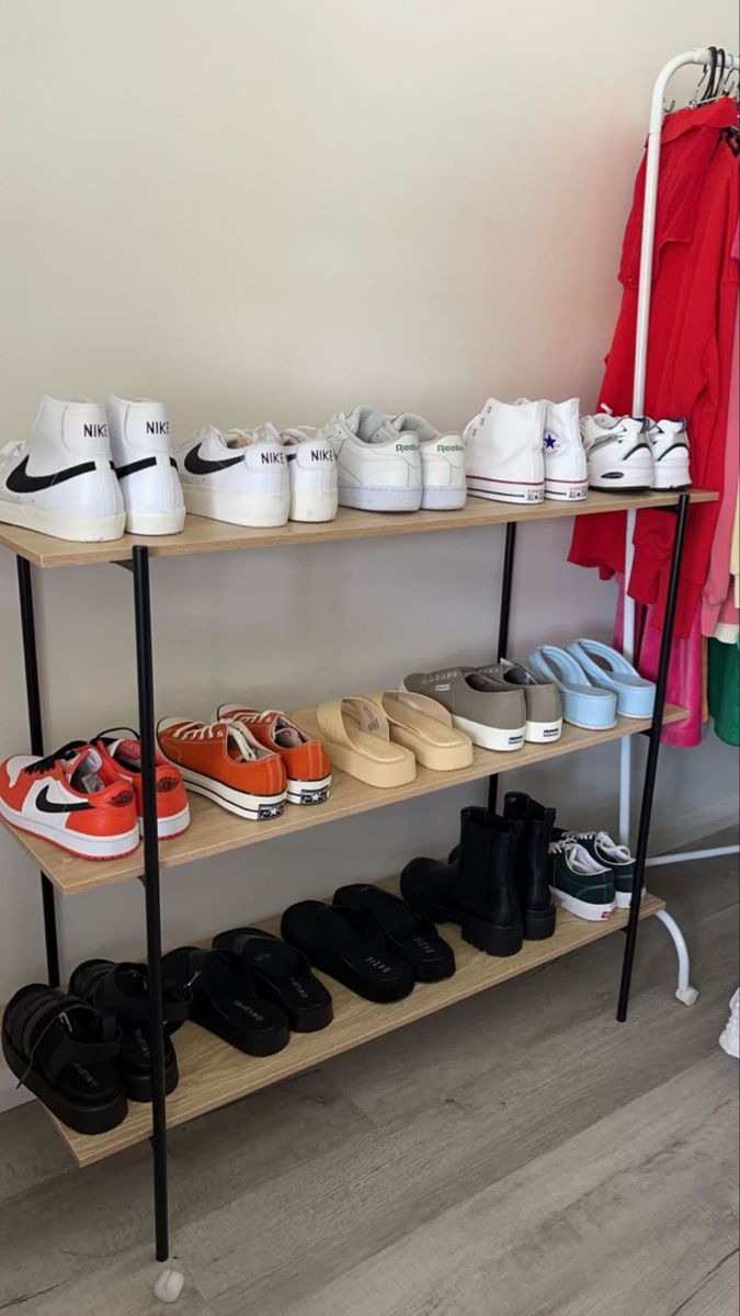 several pairs of shoes are lined up on a shelf next to a rack with clothes